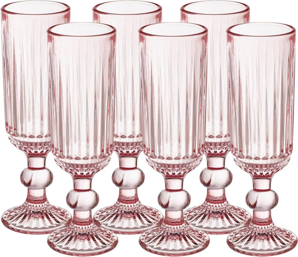 Six cranberry glass goblets with pink-tinted, ribbed bowls and decorative stems are arranged in two rows against a white background.