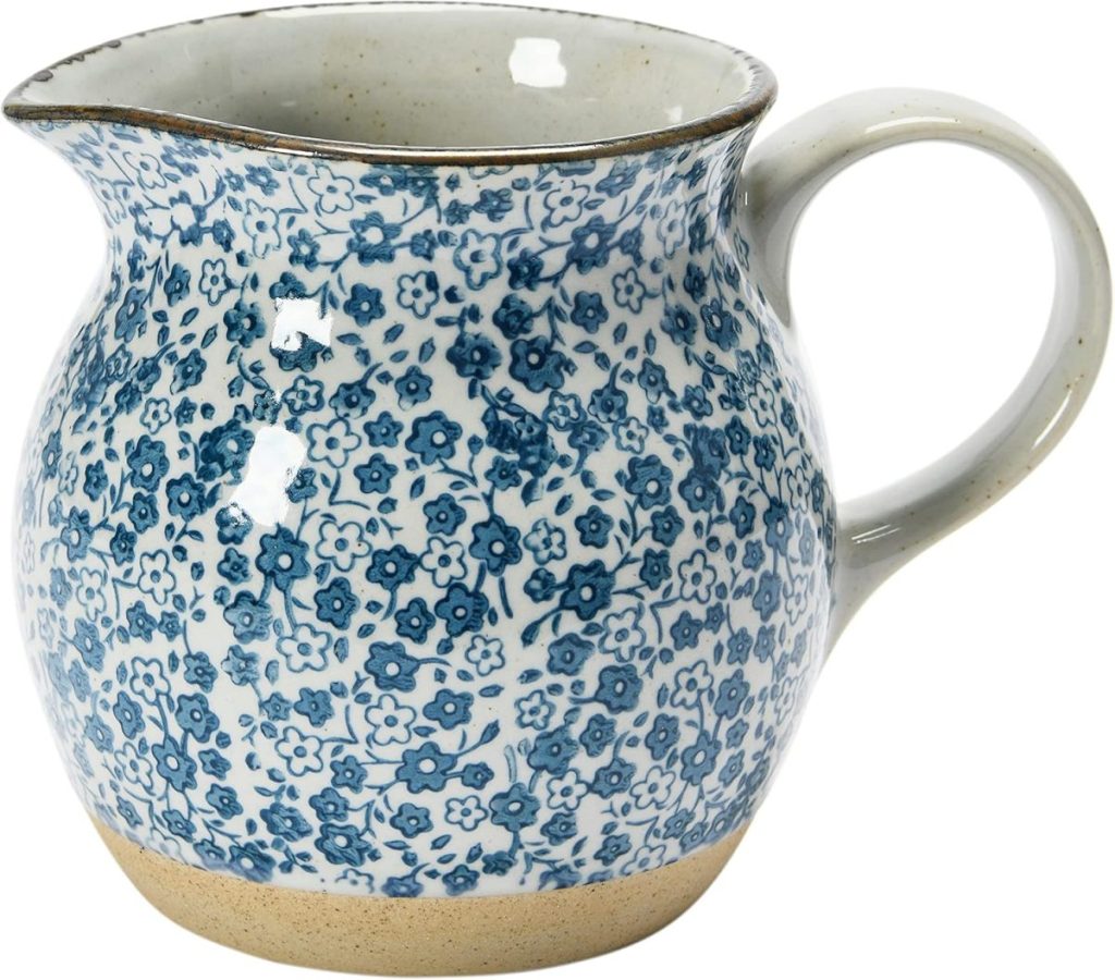 A ceramic jug with a handle, decorated with a blue floral pattern and a beige base—an ideal house guest gift.