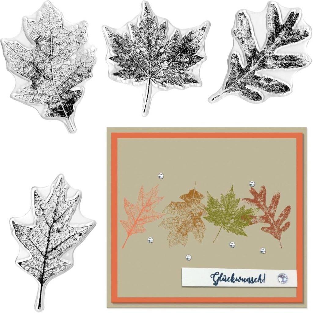 Four detailed leaf stamps are displayed above a handmade card featuring stamped leaf designs and the word "Glückwunsch!" with decorative gems—perfect inspiration for your next fall table runner project.
