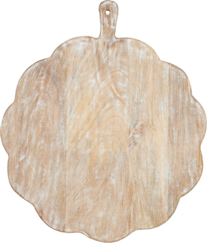 A round, scalloped wooden cutting board with a handle and a small hole for hanging, perfect for displaying your fresh batch of fall cookies on a white background.