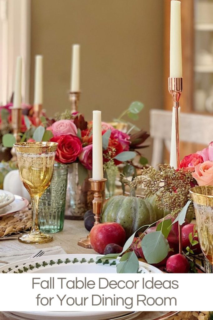 A dining table decorated with flowers, candles, pumpkins, and fruit, featuring gold-rimmed glasses and a sign reading "Fall Table Decor Ideas for Your Dining Room.