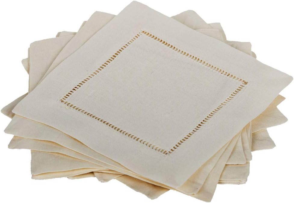 A stack of beige cloth napkins with a hemstitch border detail, perfectly paired with elegant plate chargers.