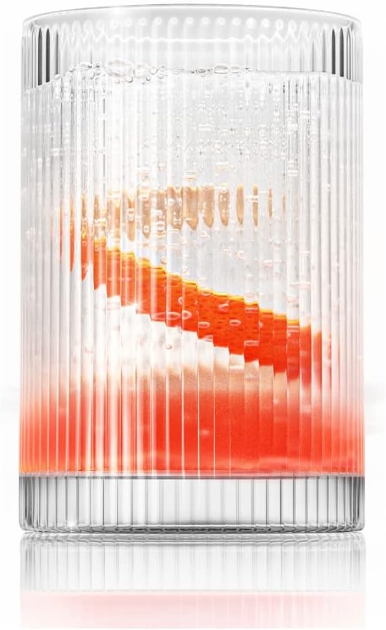 A ribbed glass, reminiscent of elegant glass water bottles, contains a beautifully layered orange and clear liquid.