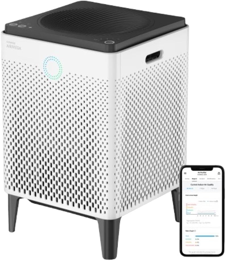 A square white air purifier with a black top is next to a smartphone displaying an air quality app.