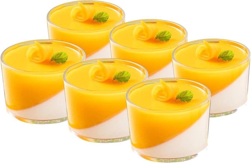 Six glass cups filled with a layered yellow and white dessert inspired by pumpkin spice latte, each topped with a yellow swirl and a small mint leaf.