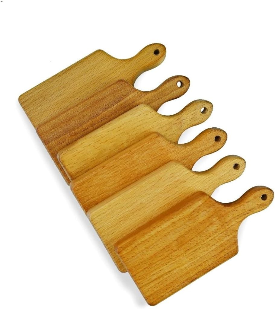 Five wooden cutting boards with handles, positioned in a slightly staggered arrangement, range in color from light to medium wood tones. Perfect as plate chargers for a rustic table setting.