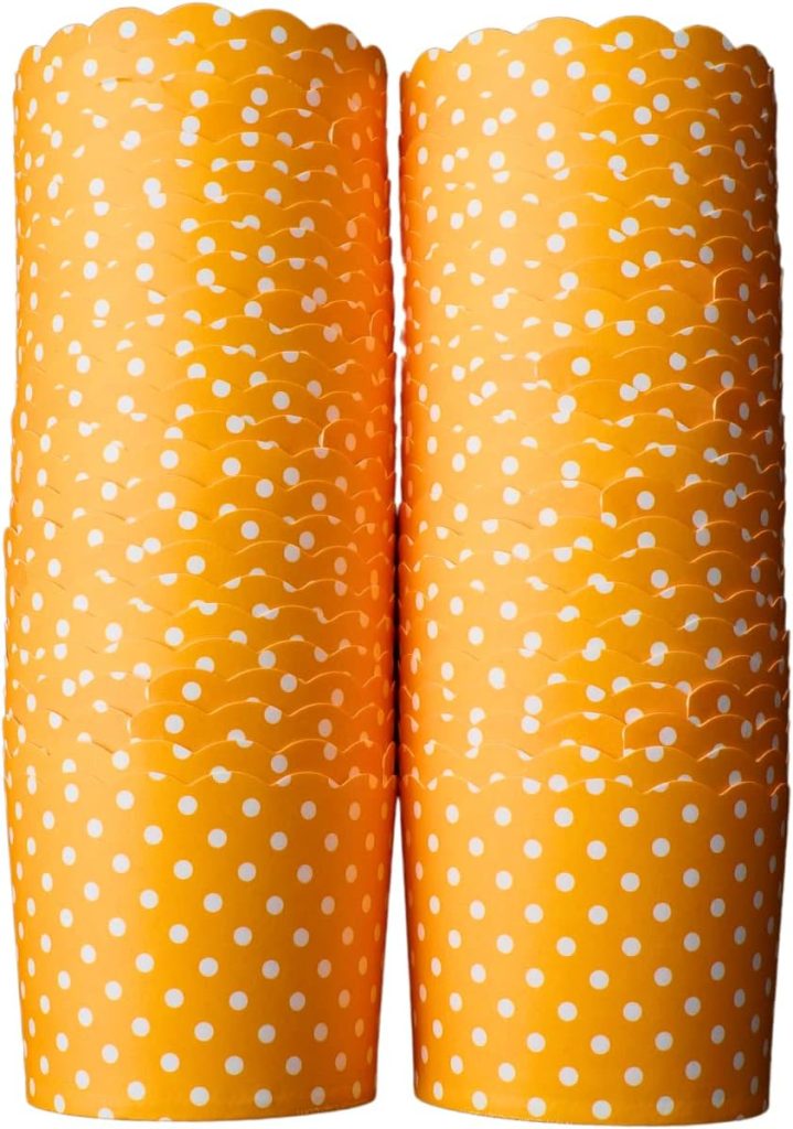 Stacks of orange paper cupcake liners with white polka dots, perfect for your favorite cupcake recipes, arranged in two columns.