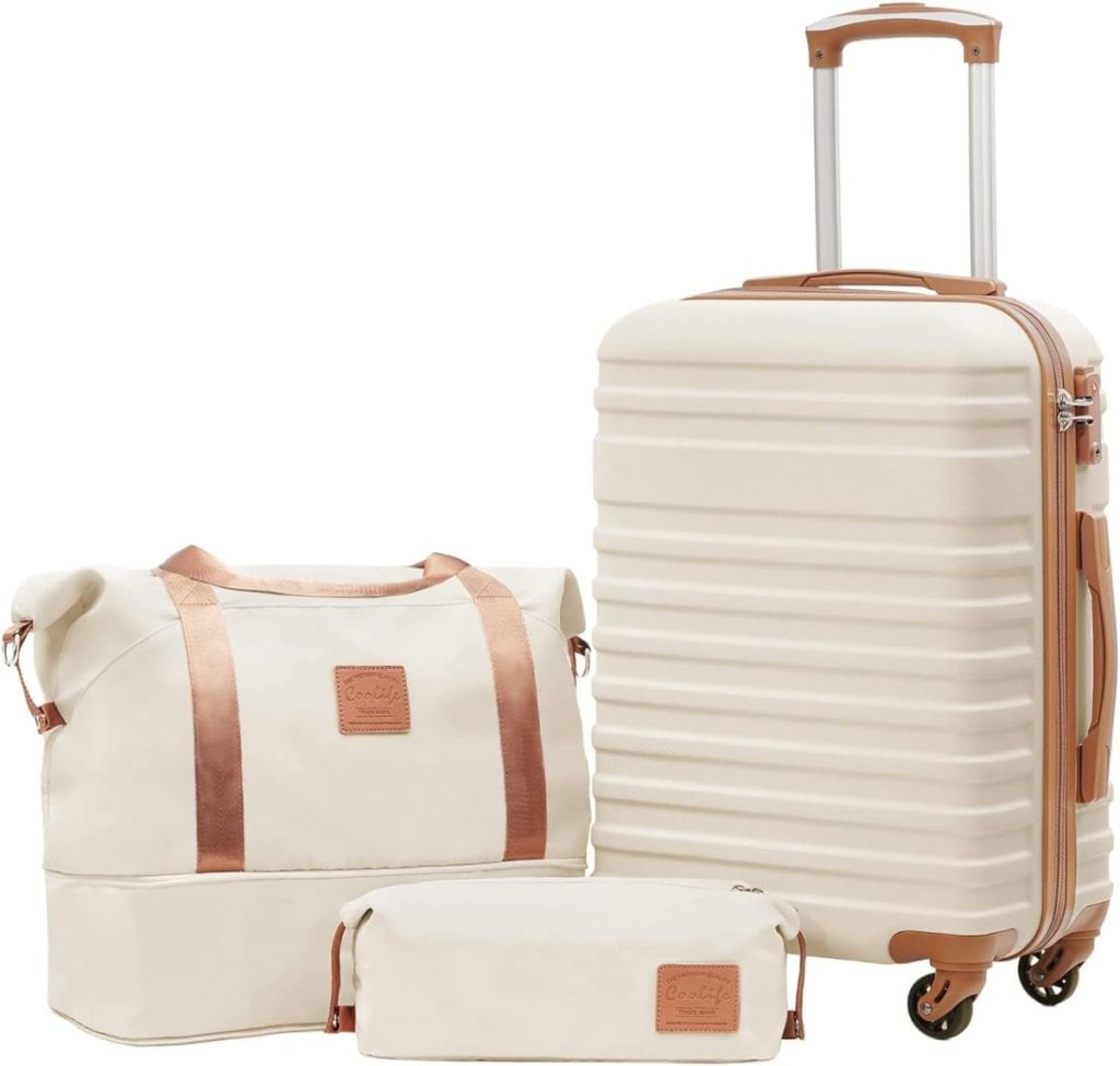 A set of three cream-colored travel bags, including a hard-shell suitcase with wheels, a large duffel bag, and a small toiletry pouch, all featuring brown handles and accents.