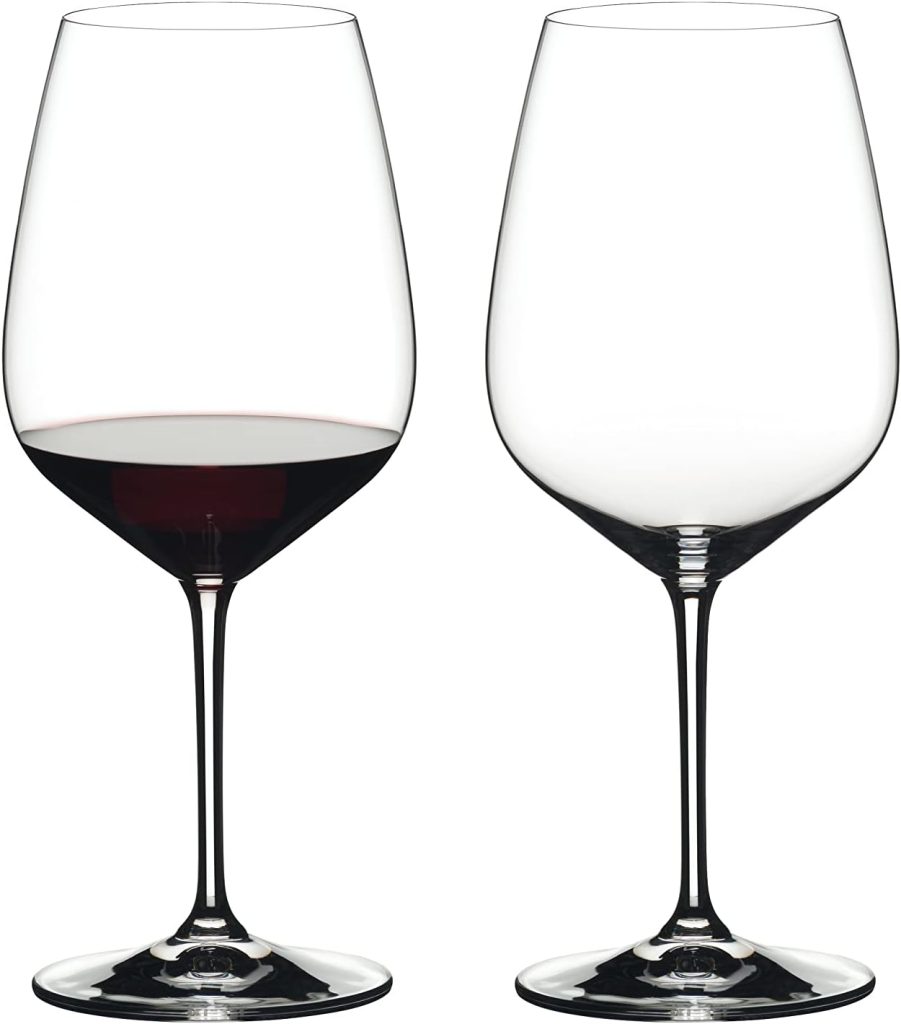 A Home to Share: A pair of wine glasses, one partially filled with red wine and the other empty, are displayed side by side against a white background.