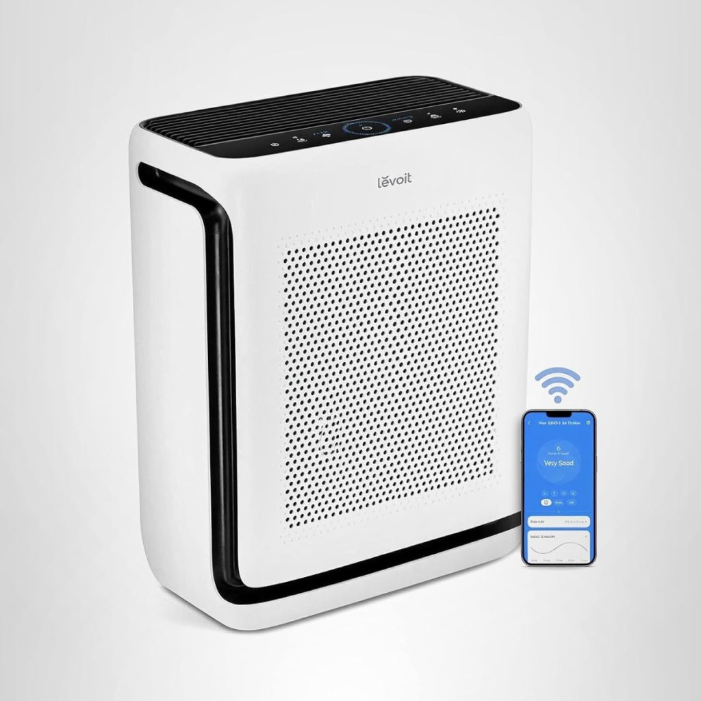 A white Levoit air purifier with control buttons on top, shown next to a smartphone displaying its app interface and a Wi-Fi symbol—perfect for keeping your space fresh during fall pumpkin season.
