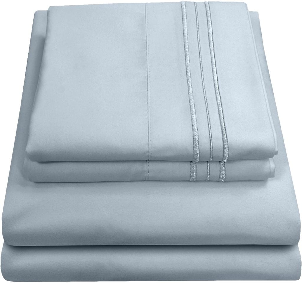 A neatly folded set of light blue bed sheets, including a fitted sheet, a flat sheet, and pillowcases with a stitched design.