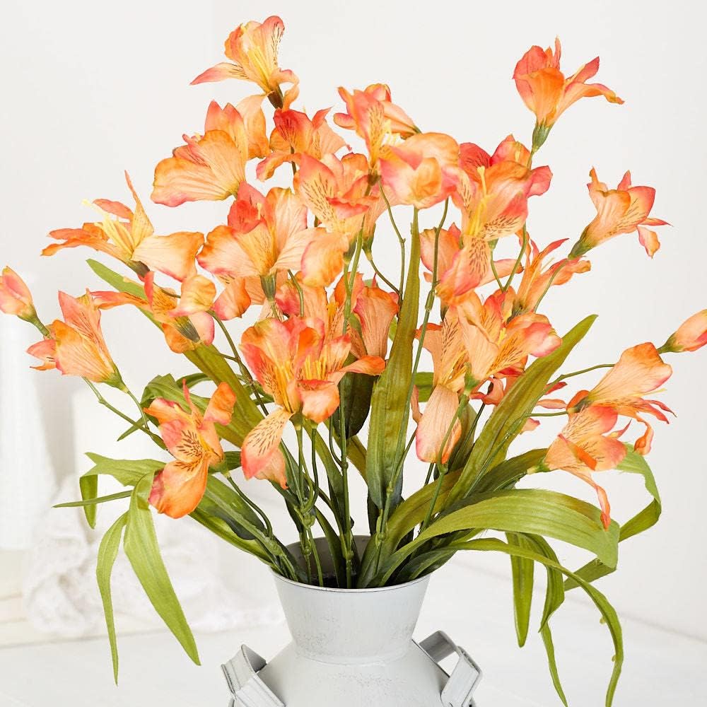 A metal vase filled with orange and yellow alstroemeria flowers creates the perfect fall flower arrangement against a light background.