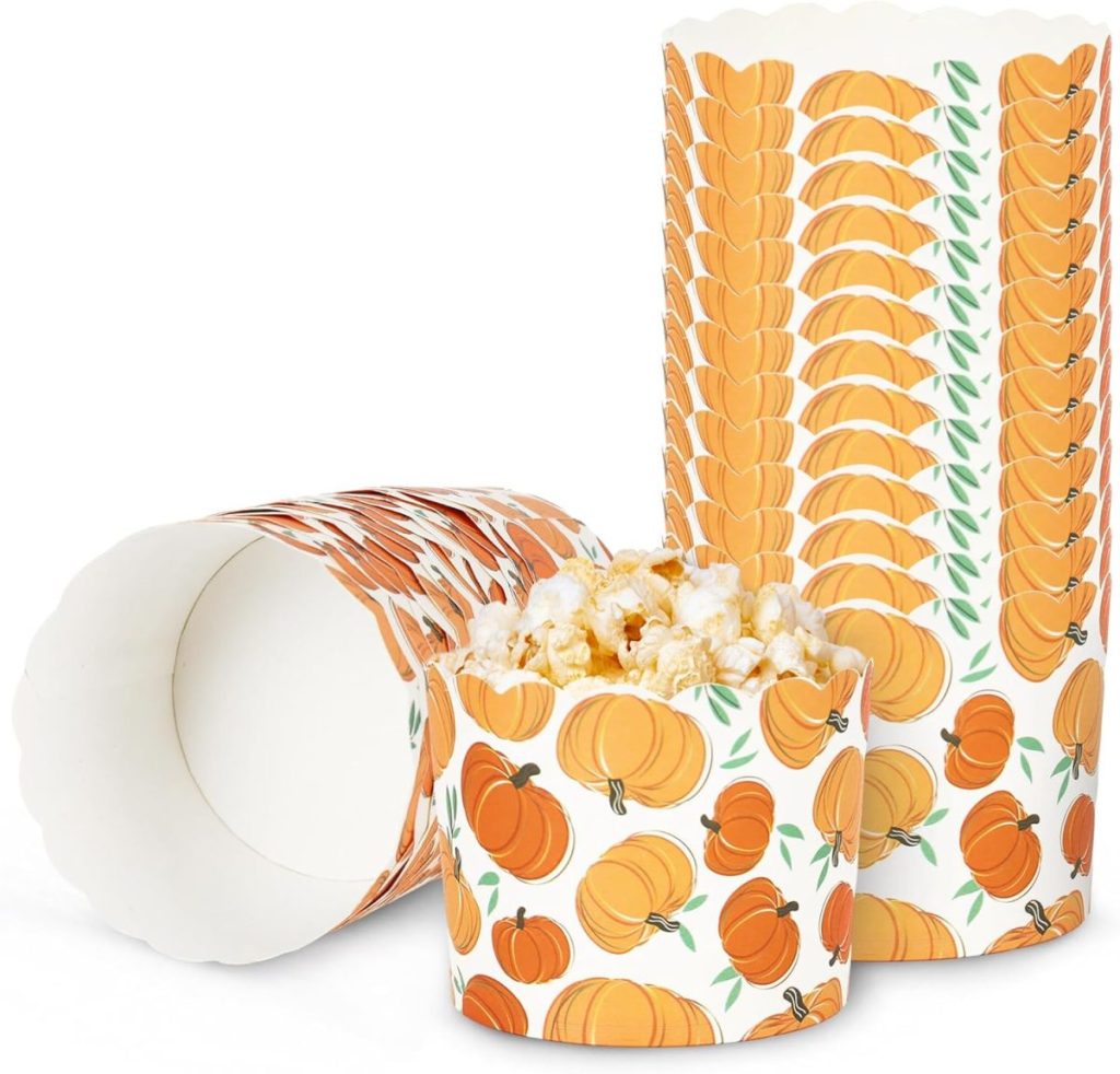 Two paper containers with pumpkin designs, one upright filled with popcorn, and the other lying on its side; perfect for holding treats while you search for new cupcake recipes.