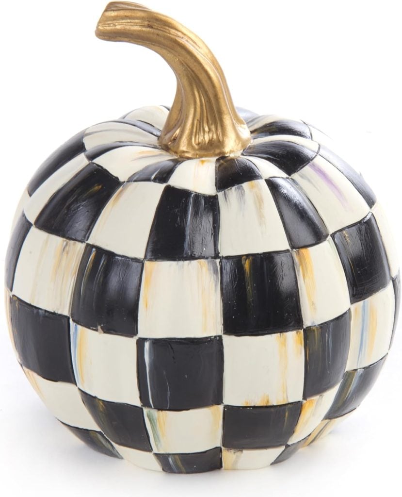 A painted pumpkin with a black and white checkered pattern and a gold stem.