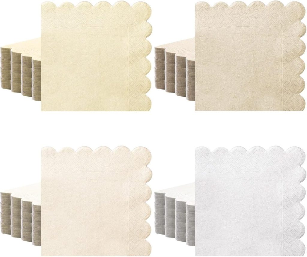 Four stacks of scalloped-edge napkins in cream, beige, light cream, and white are neatly arranged in a row—perfect for adding A Home to Share touch to your table setting.
