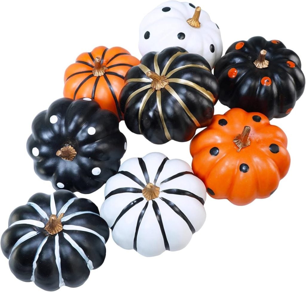 A collection of painted pumpkins in black, white, and orange, adorned with stripes and polka dots.