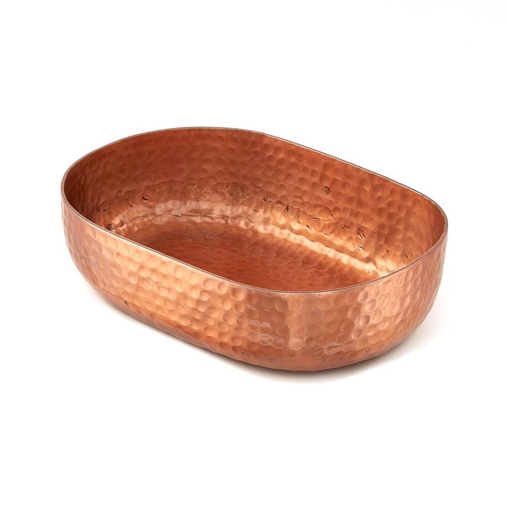 An oval-shaped, hammered copper bowl sits against a white background, perfect for displaying fall flower arrangements.