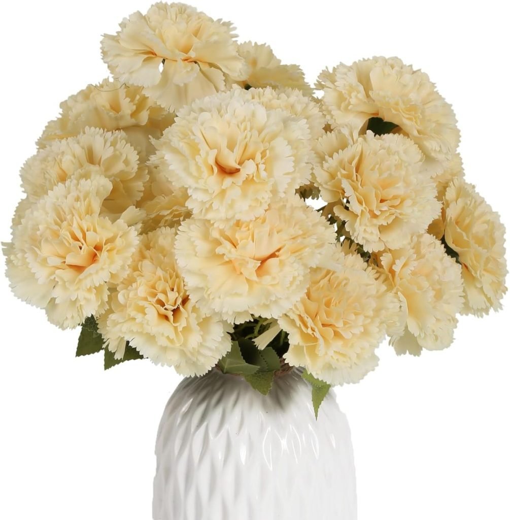 A white vase holds an arrangement of pale yellow carnations with green leaves, perfect for enhancing fall flower arrangements.