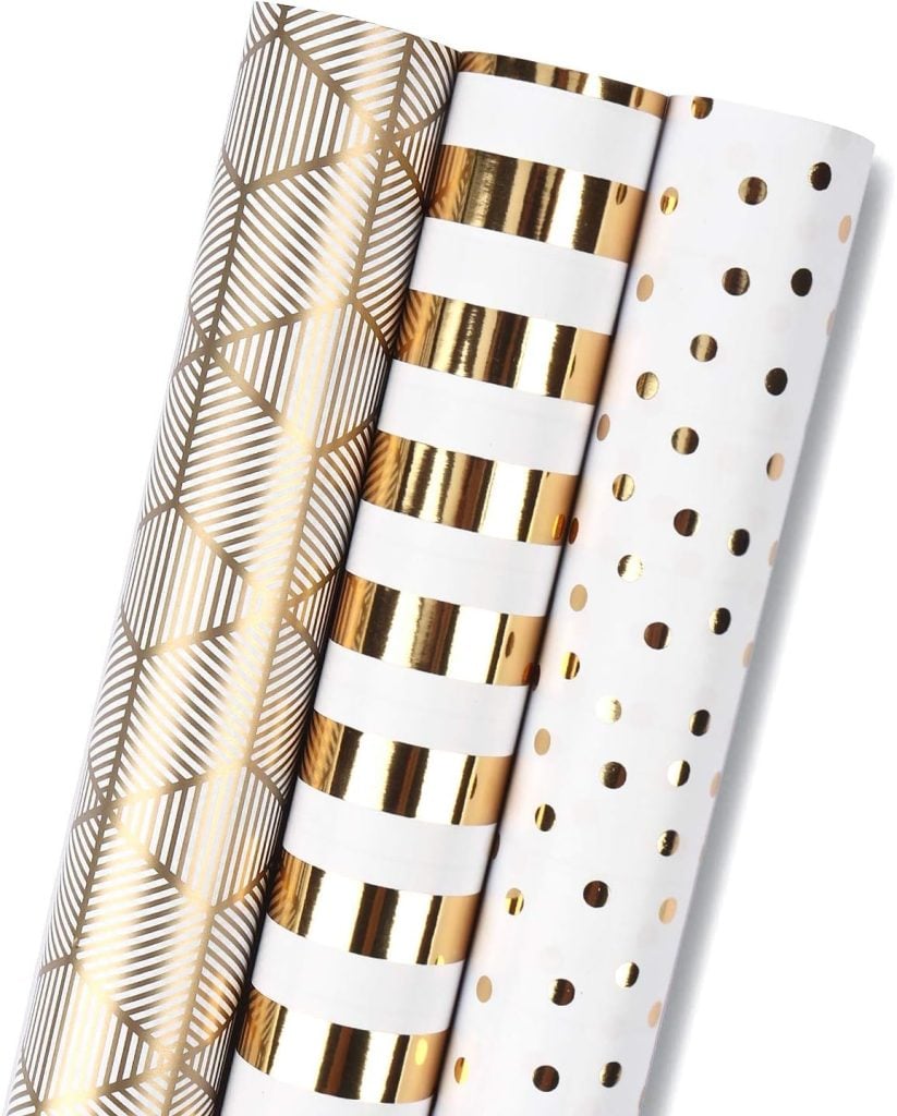 Three rolls of wrapping paper with gold geometric, striped, and polka dot patterns on white backgrounds.