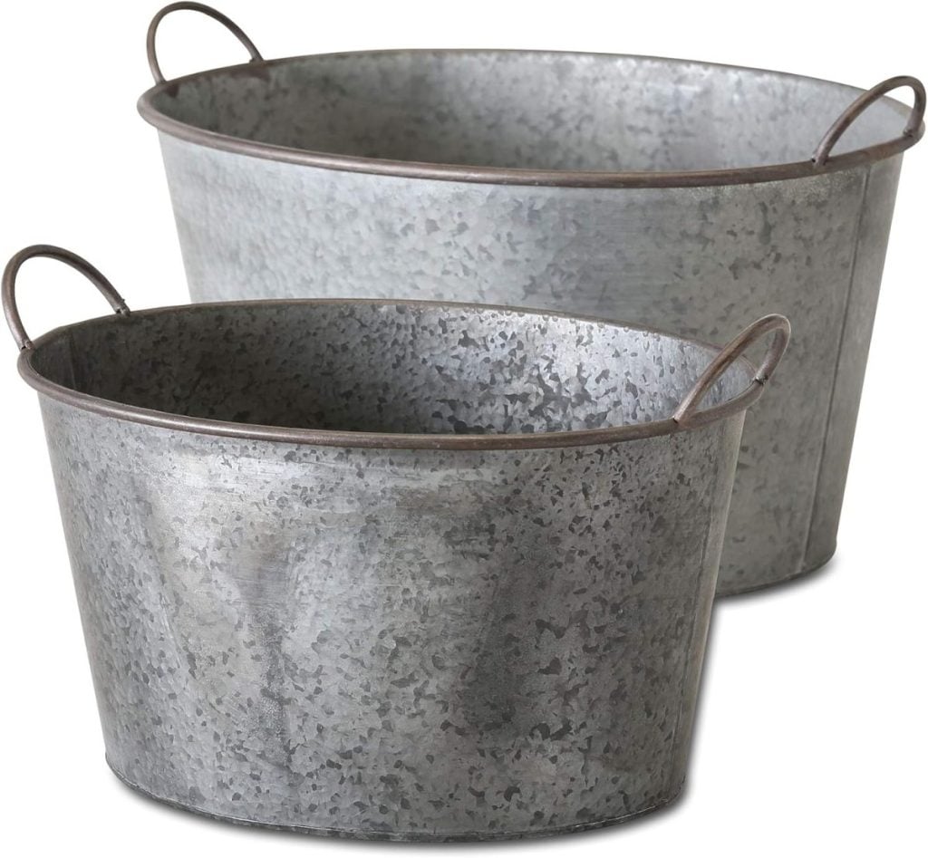 Two galvanized metal tubs with handles, perfect for fall flower arrangements, one slightly smaller and nested inside the other.