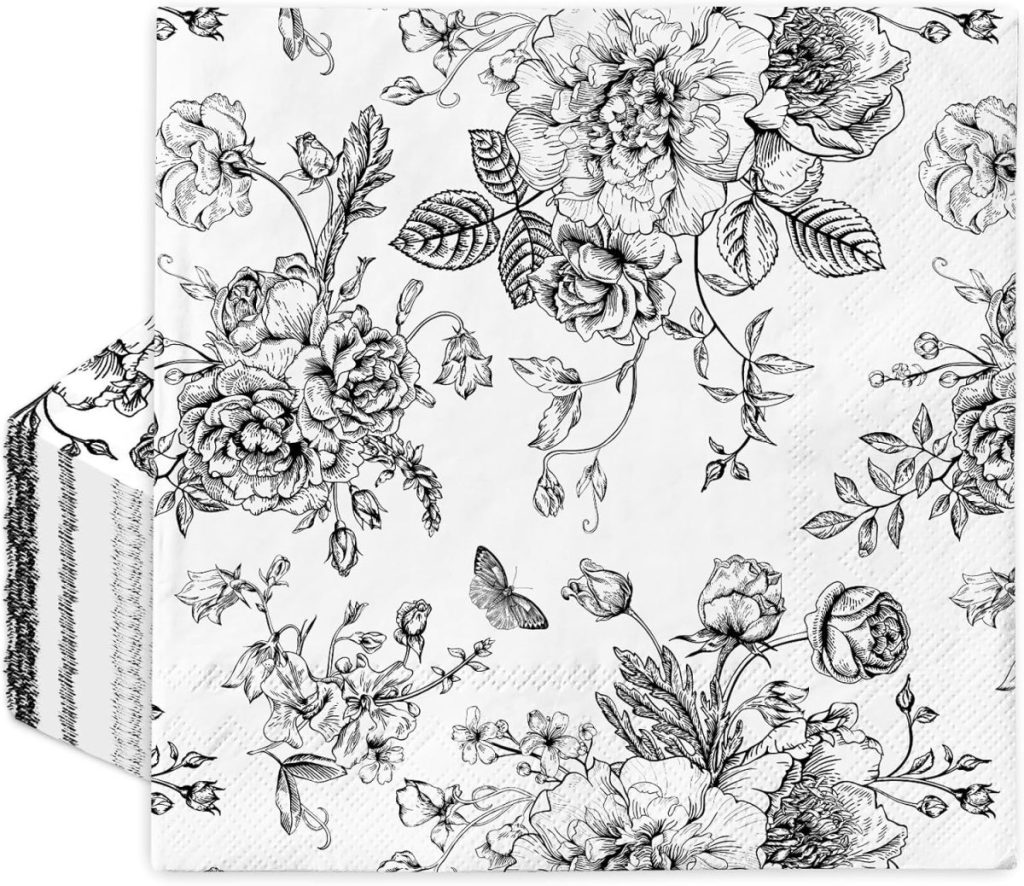 A decorative black and white floral-patterned napkin featuring various flowers, leaves, and a butterfly, perfect for pairing with wood charger plates for an elegant dining setup.