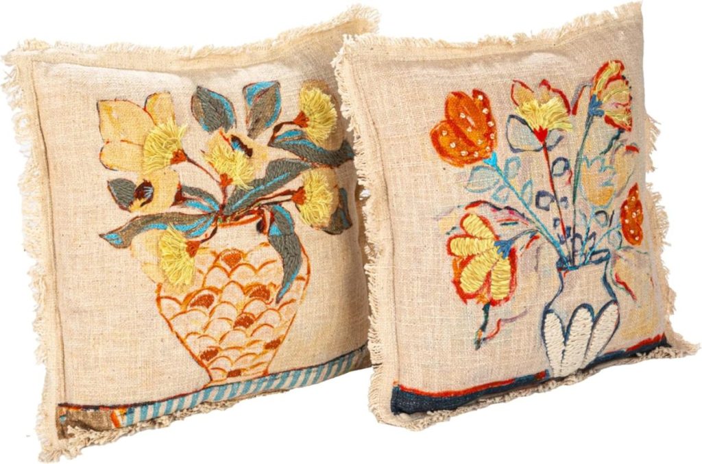 Two square Fall Pillow Covers with frayed edges, featuring embroidered floral designs in vases on a beige fabric background.