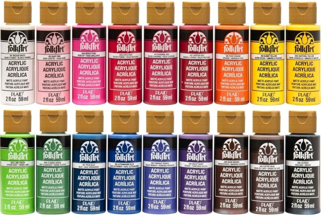 A display of 18 bottles of FolkArt acrylic paint in various colors, arranged in three rows. Each bottle is 2 fl oz (59 ml) and labeled with the brand and contents, perfect for adding vibrant designs to wood charger plates.