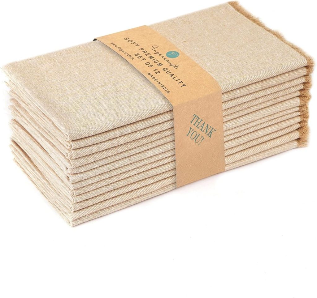 A stack of beige cloth napkins with a brown paper band labeled "Premium Soft Linen Quality" sits elegantly beside sleek glass water bottles, exuding a sense of understated luxury.