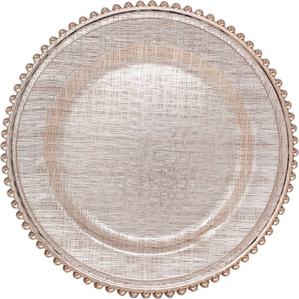 A round, metallic charger plate with a textured surface and a beaded rim design, photographed from above, beautifully contrasts with classic wood charger plates for an elegant table setting.