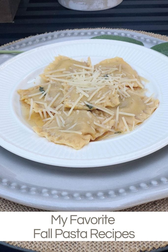 A white plate with ravioli topped with shredded cheese, placed on a larger white plate. Text at the bottom reads "My Favorite Fall Pasta Recipes.