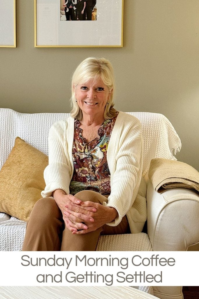 A woman sits on a white sofa with a beige throw pillow, smiling with hands clasped. Text overlay reads, "Sunday Morning Coffee and Getting Settled.