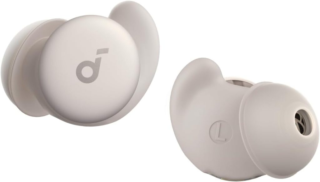 Close-up of two beige wireless earbuds, one displaying a logo and the other marked with a left ear indicator, now available with Amazon Prime for fast delivery.