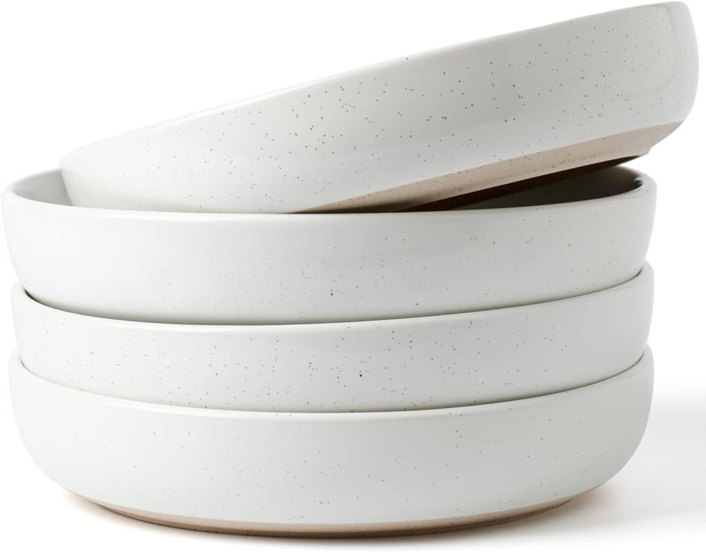 Four stacked white ceramic bowls with a speckled pattern, perfect for serving fettuccini, with the top bowl tilted and resting on the others.