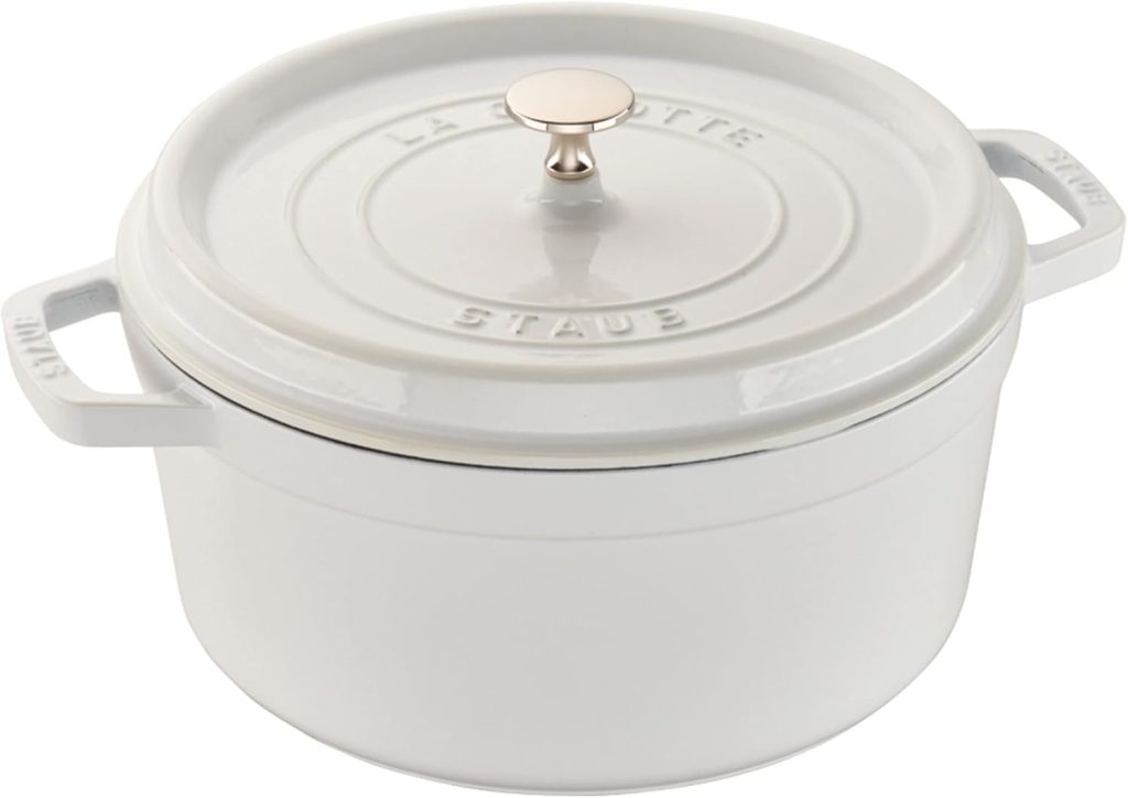 A white round cast iron Dutch oven with a lid and side handles, perfect for fall soup recipes, featuring the brand name "Staub" embossed on the rim.
