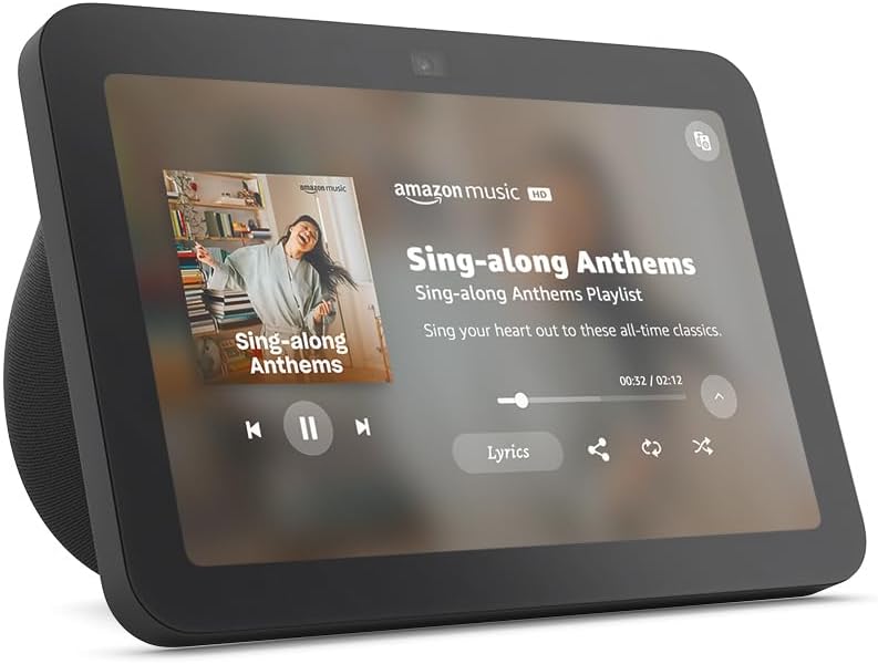 A smart display showing Amazon Music app playing "Sing-along Anthems" with album art and playback controls visible on the screen.