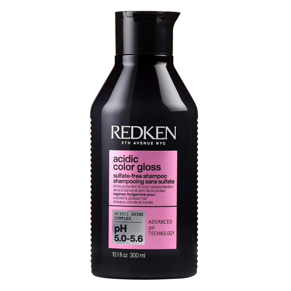 A bottle of Redken acidic color gloss sulfate-free shampoo, 300 ml, available on Amazon Prime, features a black cap and pink label detailing pH balance and benefits.