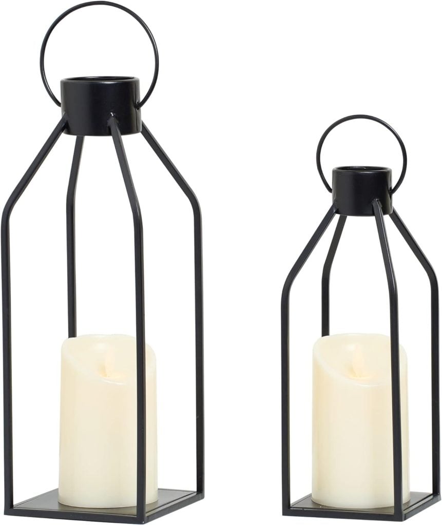 Two black metal lanterns of different heights, each holding a white candle, are perfect for adding elegance to any space. Available on Amazon Prime for quick and convenient delivery.