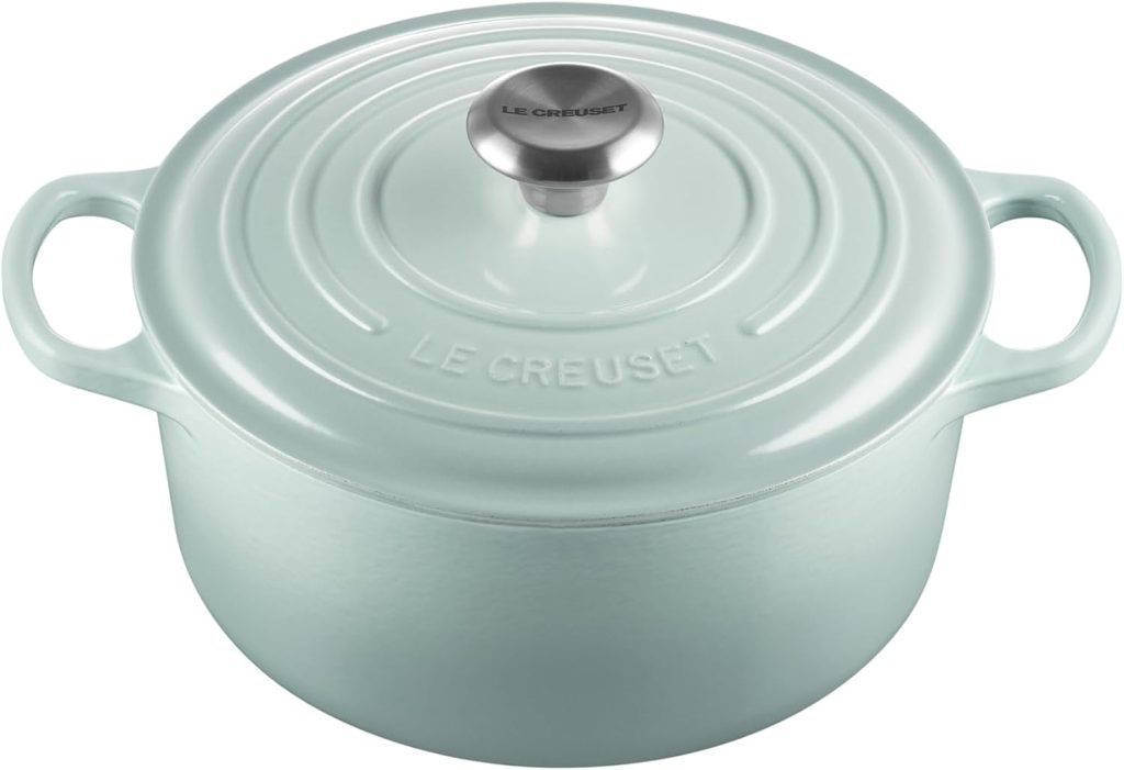 A light blue Le Creuset cast iron Dutch oven with a lid and metal knob, perfect for simmering your favorite fall soup recipes, shown on a white background.
