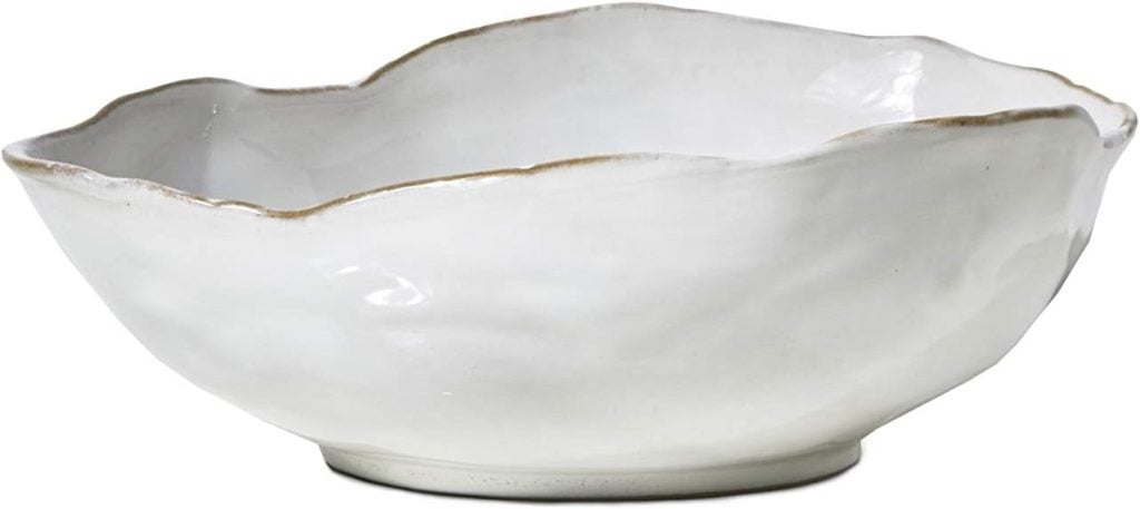 A white, ceramic bowl with an uneven wavy rim and textured surface.