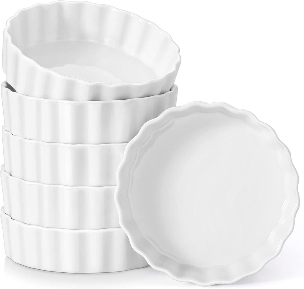 Stack of six white ceramic ramekins with ridged edges, perfect for serving a delightful pie for breakfast.