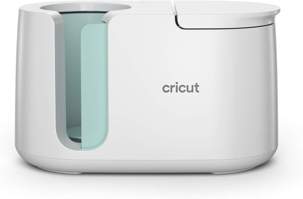 A white Cricut mug press, available on Amazon Prime, features a curved opening on the side and proudly displays the Cricut logo on the front.