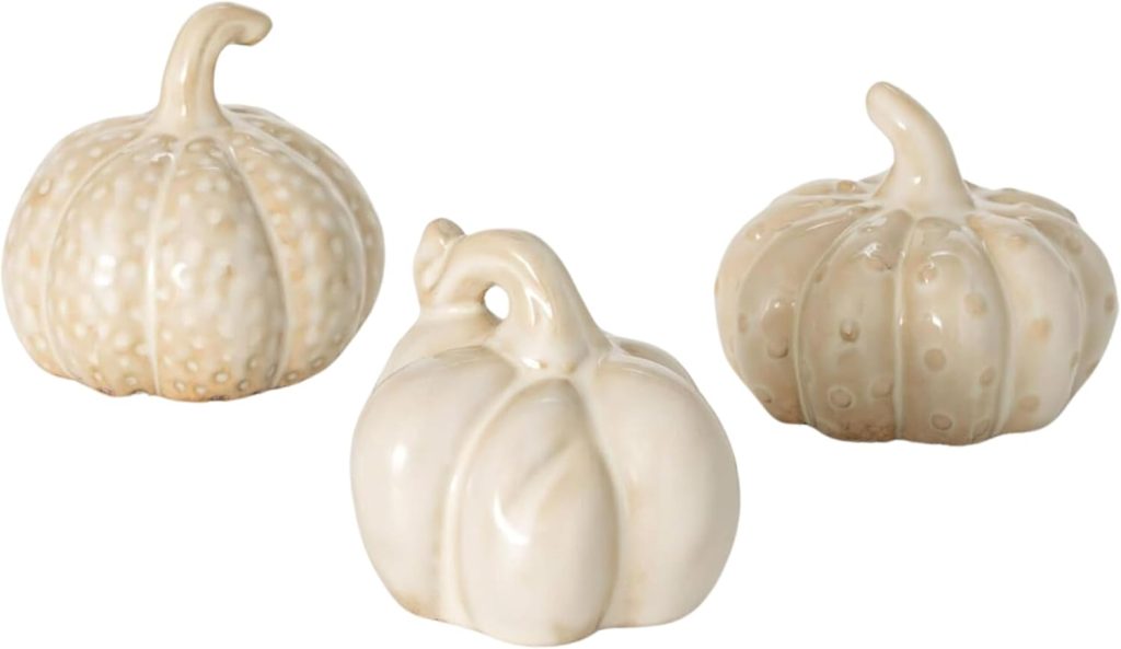 Three small, white ceramic pumpkins with varying textures and shapes.