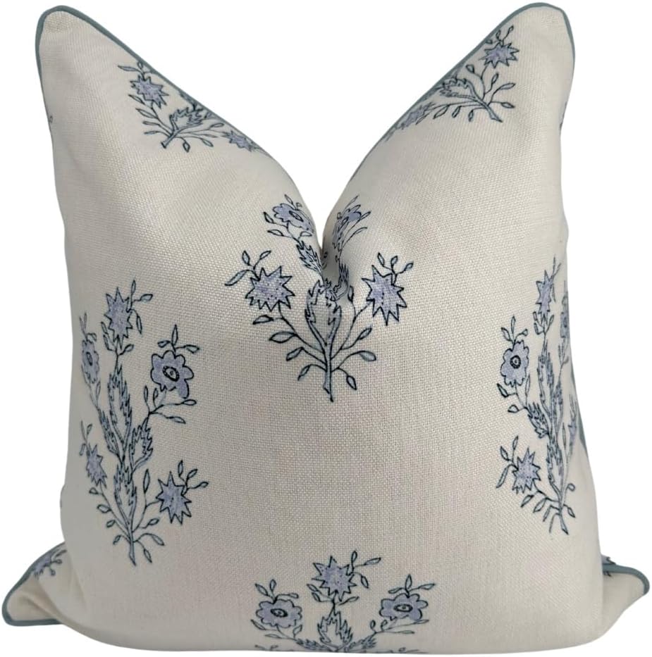 A square, beige throw pillow with blue floral embroidery, displayed against a plain white background.