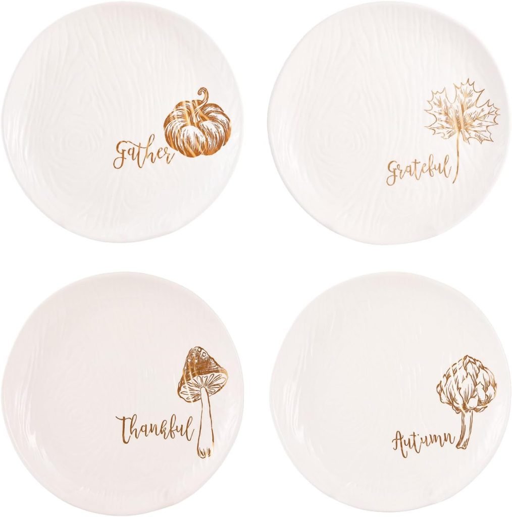 Four white Thanksgiving plates feature charming illustrations: a pumpkin labeled "Gather," a maple leaf labeled "Grateful," a mushroom labeled "Thankful," and an artichoke labeled "Autumn.