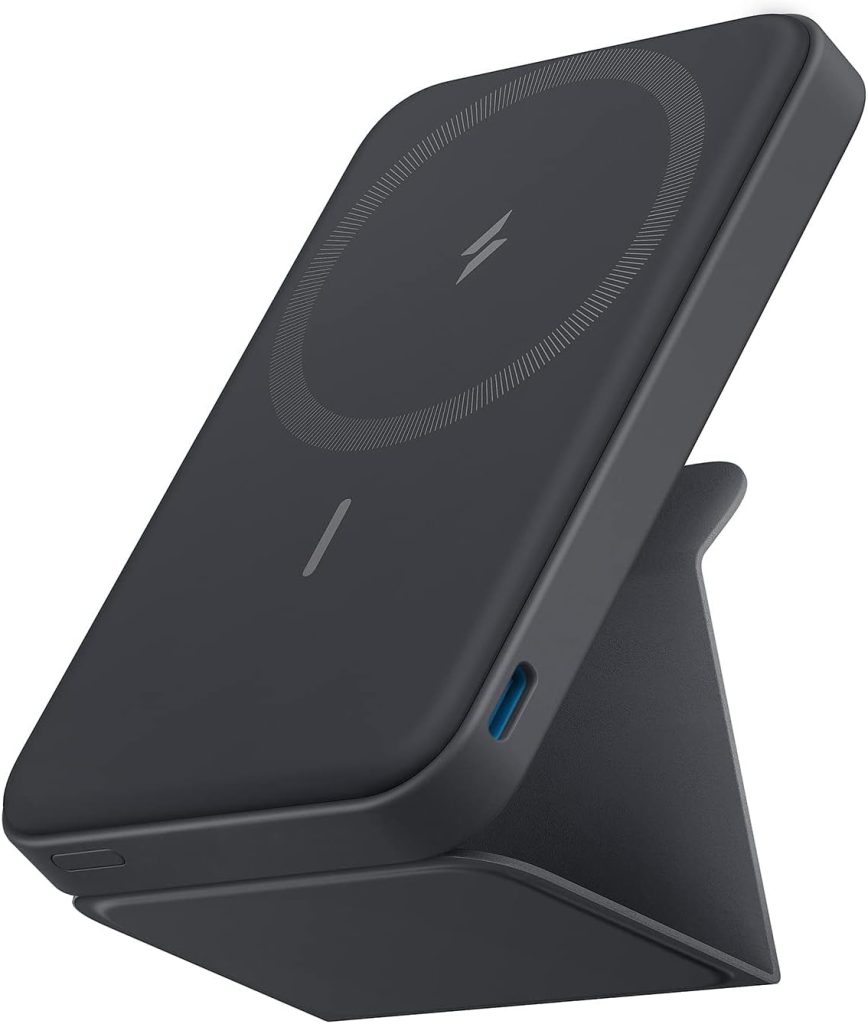 A dark gray portable wireless charger with a circular charging area, positioned upright on a foldable stand, is available exclusively with Amazon Prime for quick delivery.