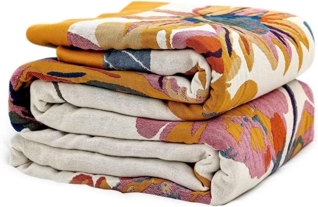 A folded fabric with a colorful floral pattern, featuring vibrant shades of yellow, pink, and blue—available for fast delivery with Amazon Prime.