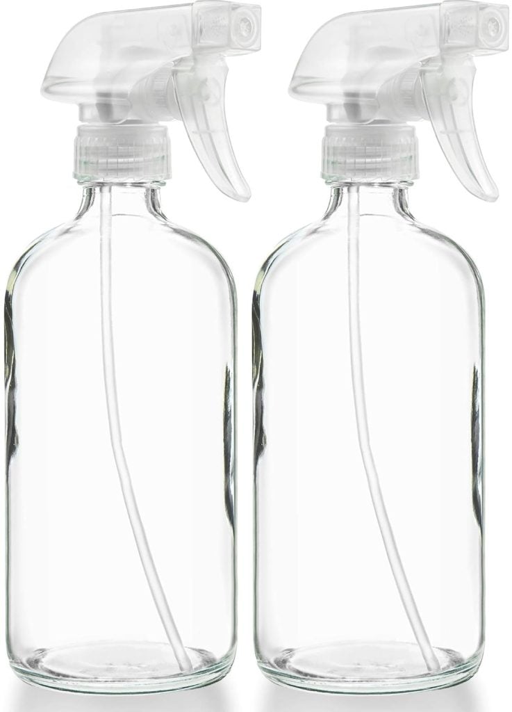 Two clear glass spray bottles with white plastic nozzles.