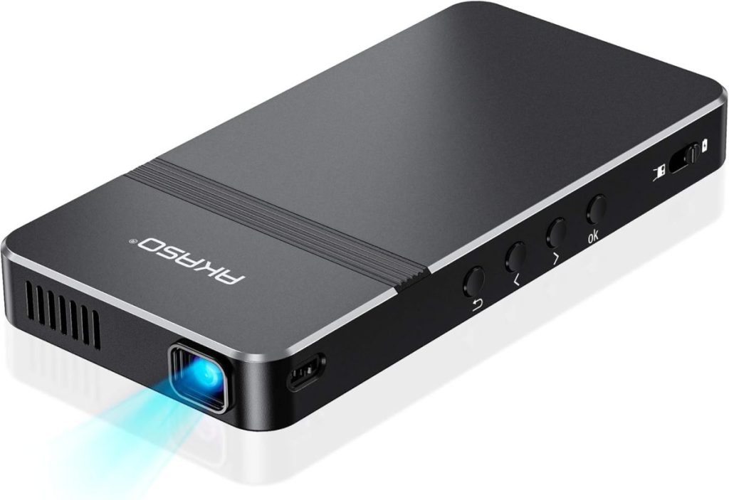 A slim, rectangular black portable projector with a lens emitting a blue light. Features include several buttons on the side and an Amazon Prime branded label on the top surface.