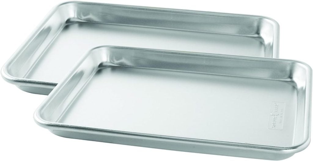 Two rectangular metal baking sheets, perfect for making Baked Brie with Jam, are placed side by side, viewed from above.