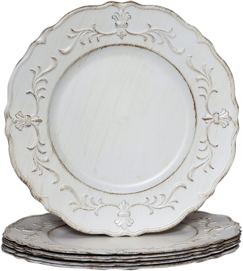 A stack of round, white decorative Thanksgiving plates with ornate embossed designs on the edges.